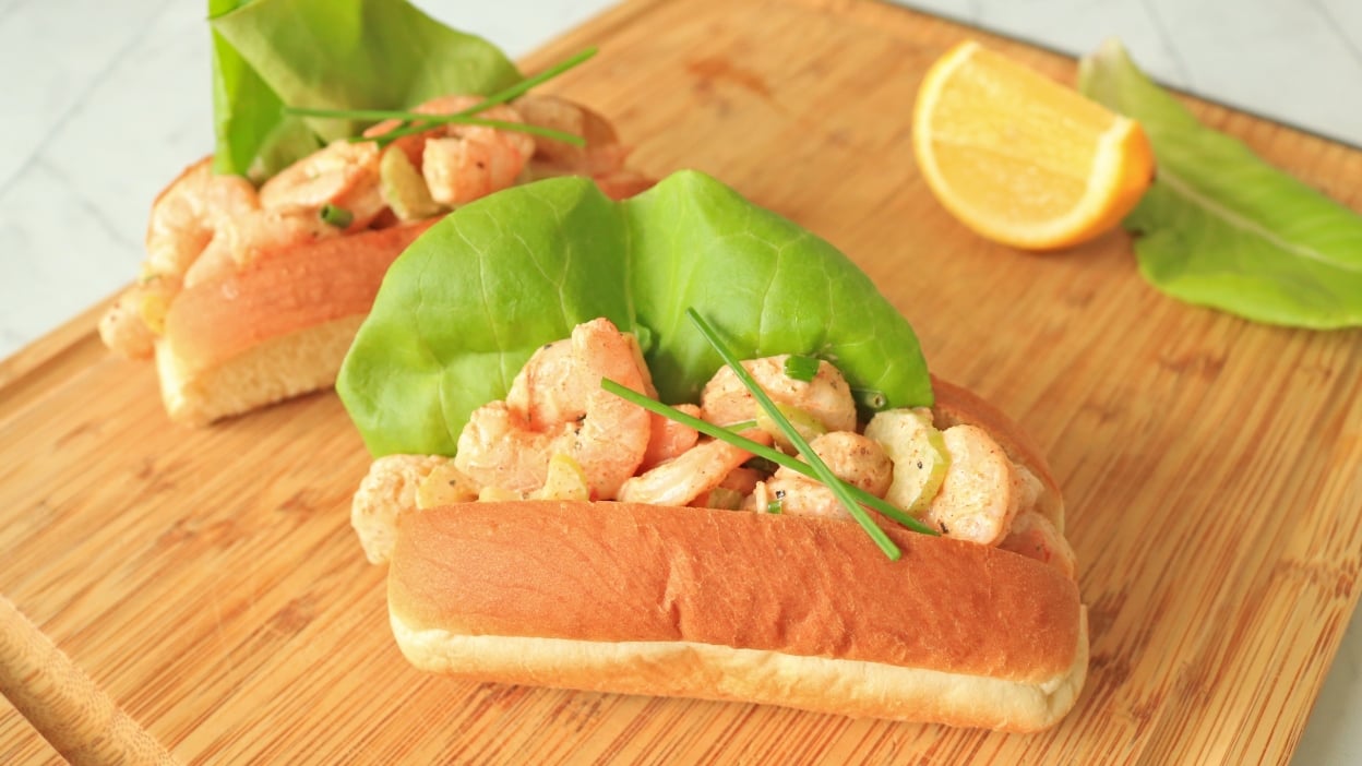 Two shrimp rolls on a cuttingboard.