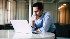 Man looking concerned, studying laptop screen