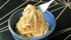 A fork picks up a heap of spaghetti and cream sauce.