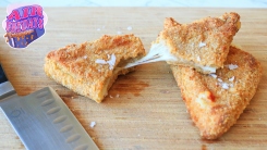 A mozzarella in carrozza sandwich on a cutting board with stretchy cheese.