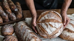 Hands holding a loaf of bread.