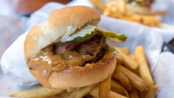 A cheeseburger with bacon, pickles, and peanut butter on a pile of fries