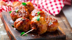 Meatballs in a glaze on a cutting board.