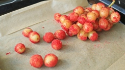 Grapes covered in red Jell-O powder on a baking sheet.