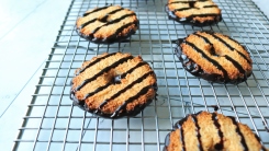 Coconut cookies with chocolate stripes on a wire cooling rack.