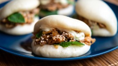 A close-up of gua bao stuffed with shredded meat on a plate.