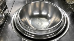 A set of nesting metal mixing bowls on a metal counter.