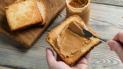 Hands spreading peanut butter on toast.