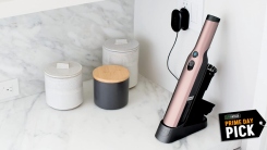 A pink cordless vacuum charging on a countertop.