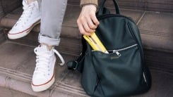 Hand pulling a granola bar from a backpack.