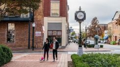 A couple walking their dog in a quaint downtown area