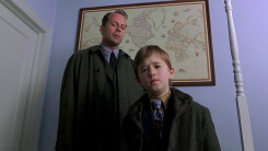 Bruce Willis and Haley Joel Osment stand in a room in a scene from The Sixth Sense