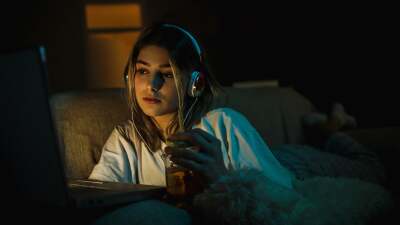 A woman watching streaming media on a laptop in a dim room