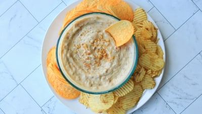 Onion dip in a bowl with chips around it on a plate