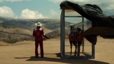 Steven Yeun stands beside a caged horse/Nope