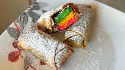 Rainbow cookie egg rolls on a plate.