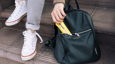 Hand pulling a granola bar from a backpack.