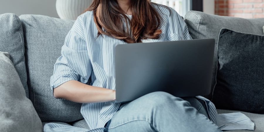 person looking at laptop on couch 