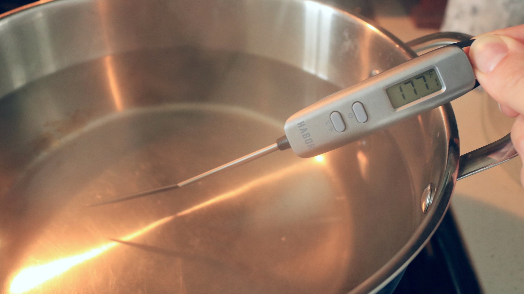 A thermometer in a pot of water reads 177 degrees.