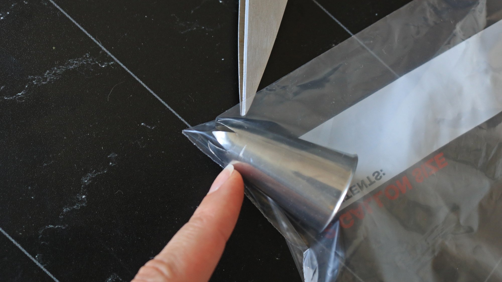 Finger pointing to a piping tip in a plastic bag.