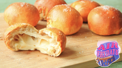 Bread balls stuffed with cheese on a cutting board.