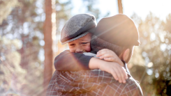 father holding and comforting young son who is crying