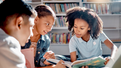 Three kids sitting together, reading a book