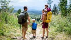 A photograph of a family of four hiking through a wooded area.