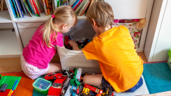 two children playing in a playroom with toys on floor