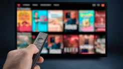 close-up of a man's hand holding a remote with tv blurred in background