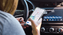 Person in the driver's seat of a car looking at Google Maps on their phone