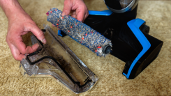 A person disassembling their vacuum and looking at a dirty roller brush.