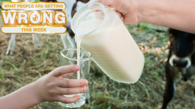 milk is poured from a jug into a glass held by children's hands