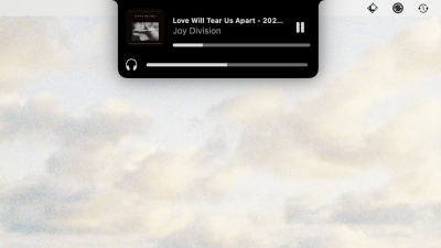 A black overlay extending from the menu bar showing the currently playing track (Love Will Tear Us Apart by Joy Division) and the current volume.