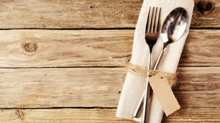 silver spoon and fork lying on a napkin on a wooden table