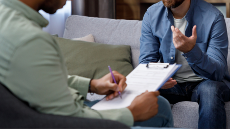 A photograph of two people talking during a therapy session